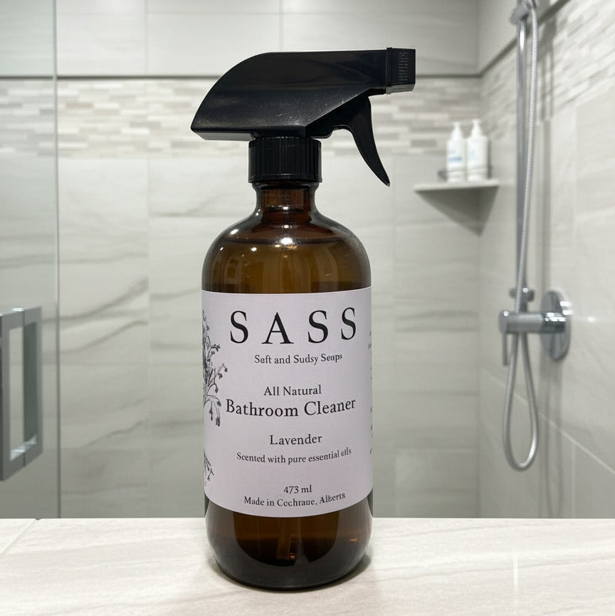 Bottle of SASS bathroom cleaner on a bathroom counter with shower in background