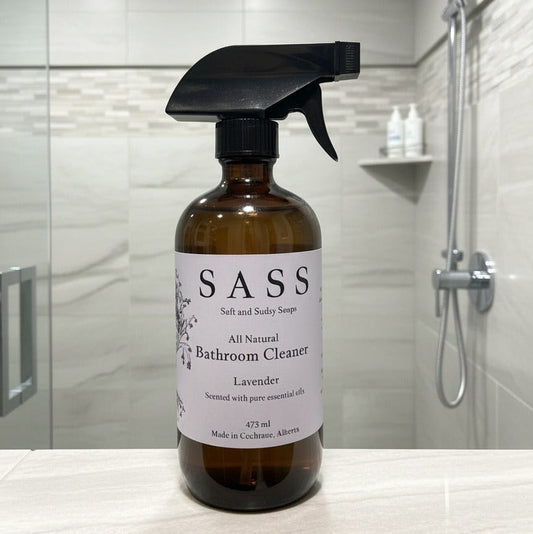 Bottle of SASS bathroom cleaner on a bathroom counter with shower in background