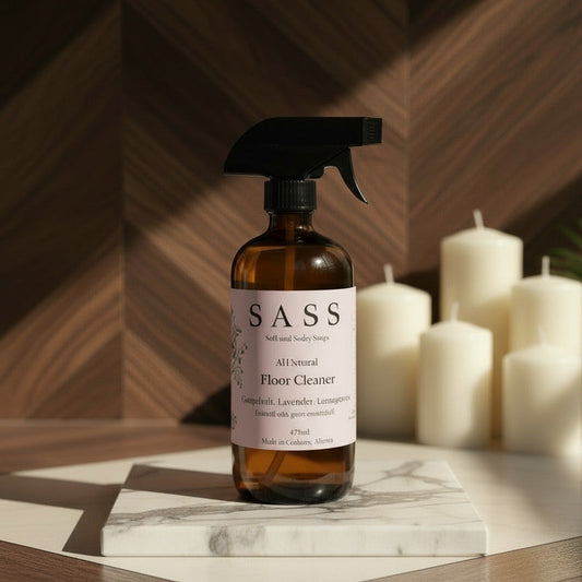 Bottle of SASS floor cleaner on a marble surface with candles in the background