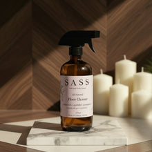 Load image into Gallery viewer, Bottle of SASS floor cleaner on a marble surface with candles in the background
