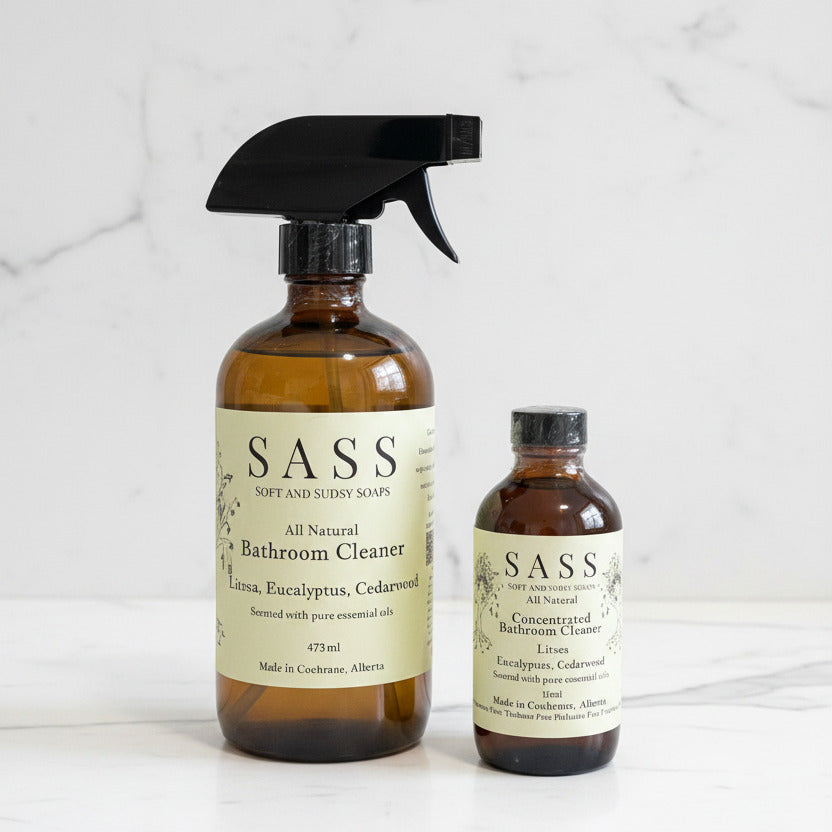 Two bottles of SASS bathroom cleaner on a white marble surface. made in canada, all natural, non toxic cleaner