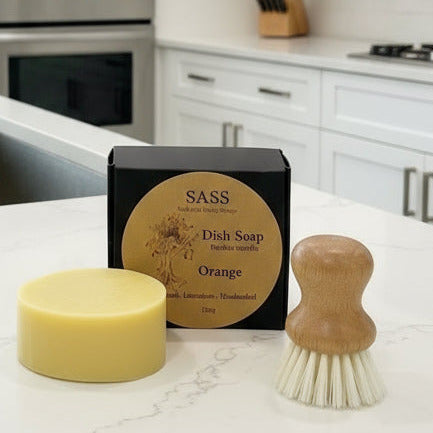 Bar of dish soap, box of dish soap, and wooden brush on a kitchen counter.