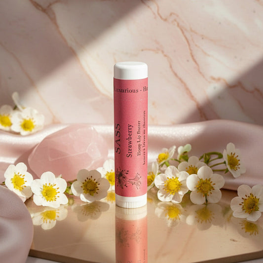 Pink lip balm with white cap on a marble surface surrounded by small white flowers